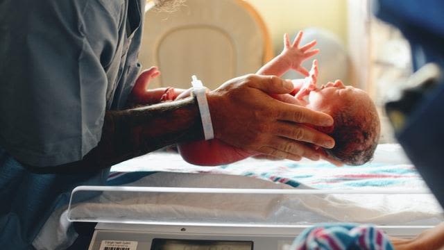 Photo of newborn baby being weighed