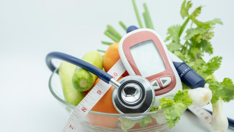 Close up of Stethoscope with Glucose meter for check blood sugar level, lancet, tape measure and green vegetable fresh tomato, cucumber coriander and spring onion.