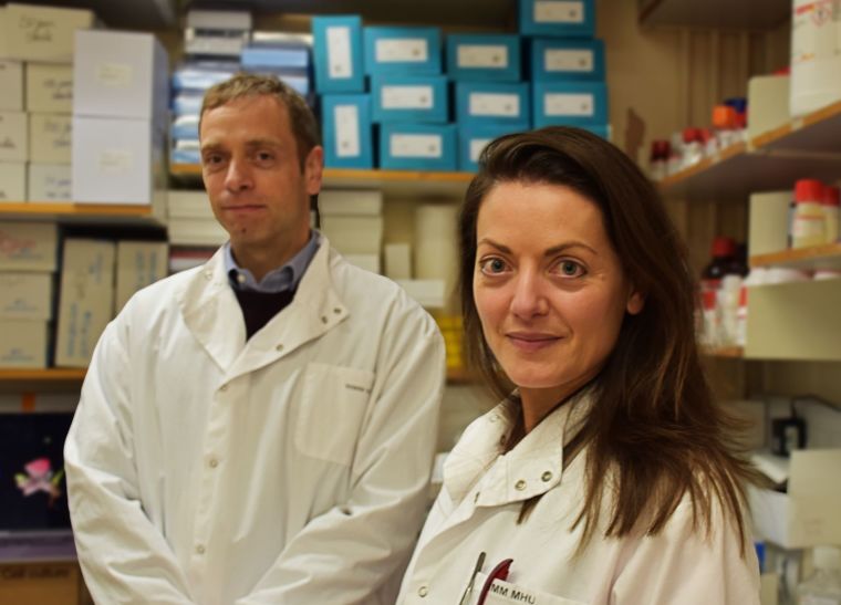 Professor Adam Mead (left) and Professor Beth Psaila wearing labcoats and surrounded by lab equipment.