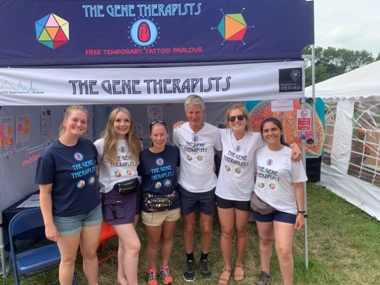 Group of men and women wearing gene-themed t-shirts in front of a gazebo saying The Gene Therapists.