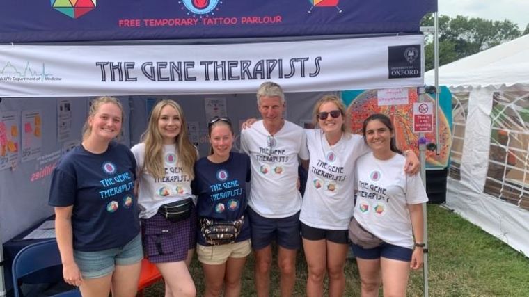Group of men and women wearing gene-themed t-shirts in front of a gazebo saying The Gene Therapists.